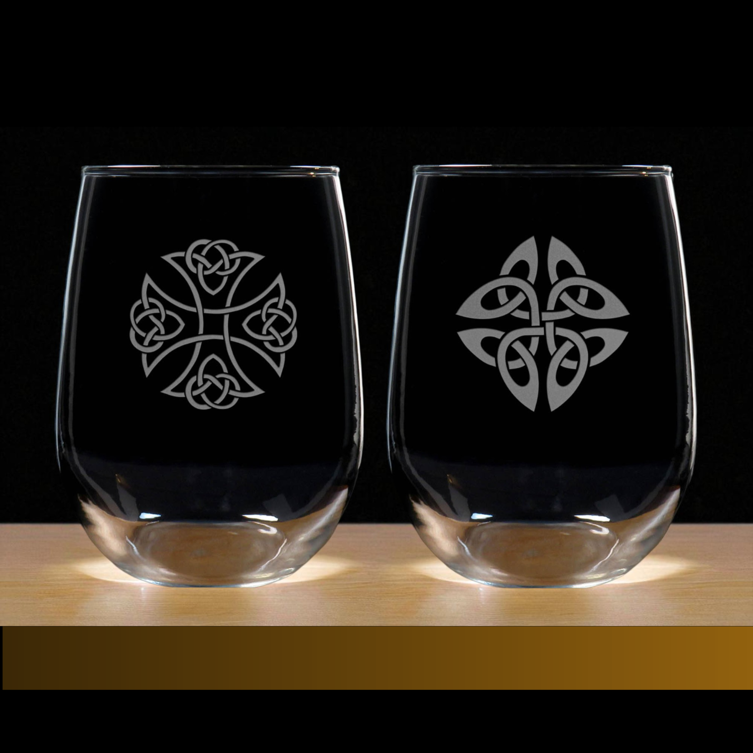 Two clear glasses with Celtic knot designs on a wooden surface and black background