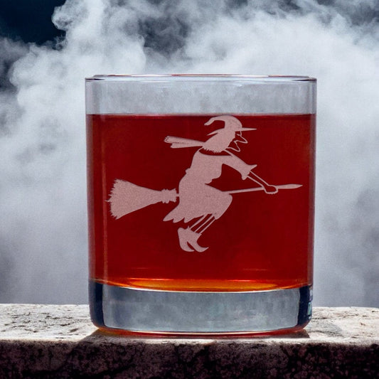 An image of an 11oz whiskey glass with a misty background with a witch on her broomstick.