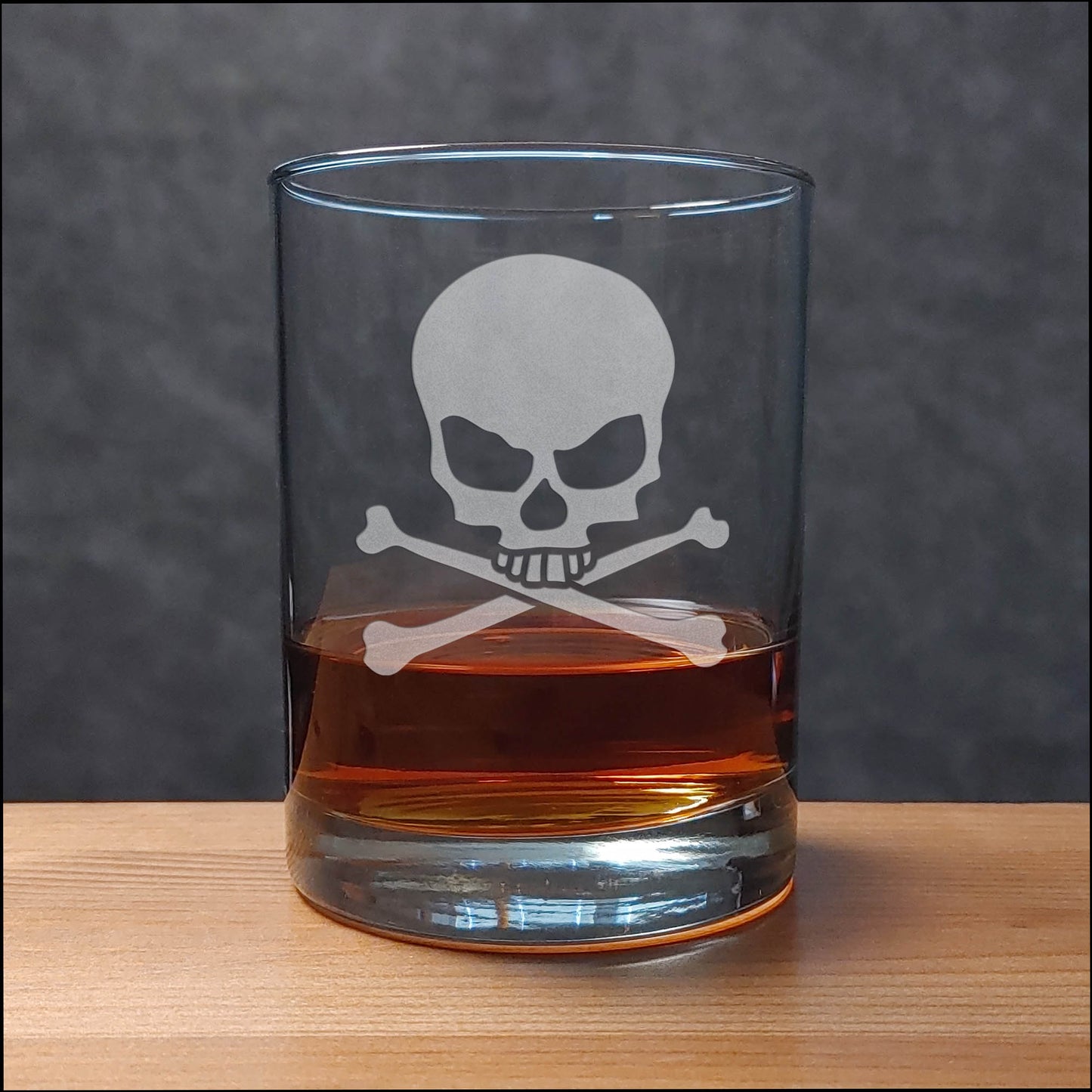 Glass with skull and crossbones design filled with a dark liquid on a wooden surface.