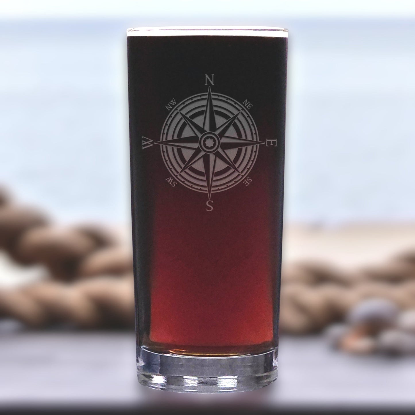 Black glass with compass design filled with red liquid on a blurred natural background