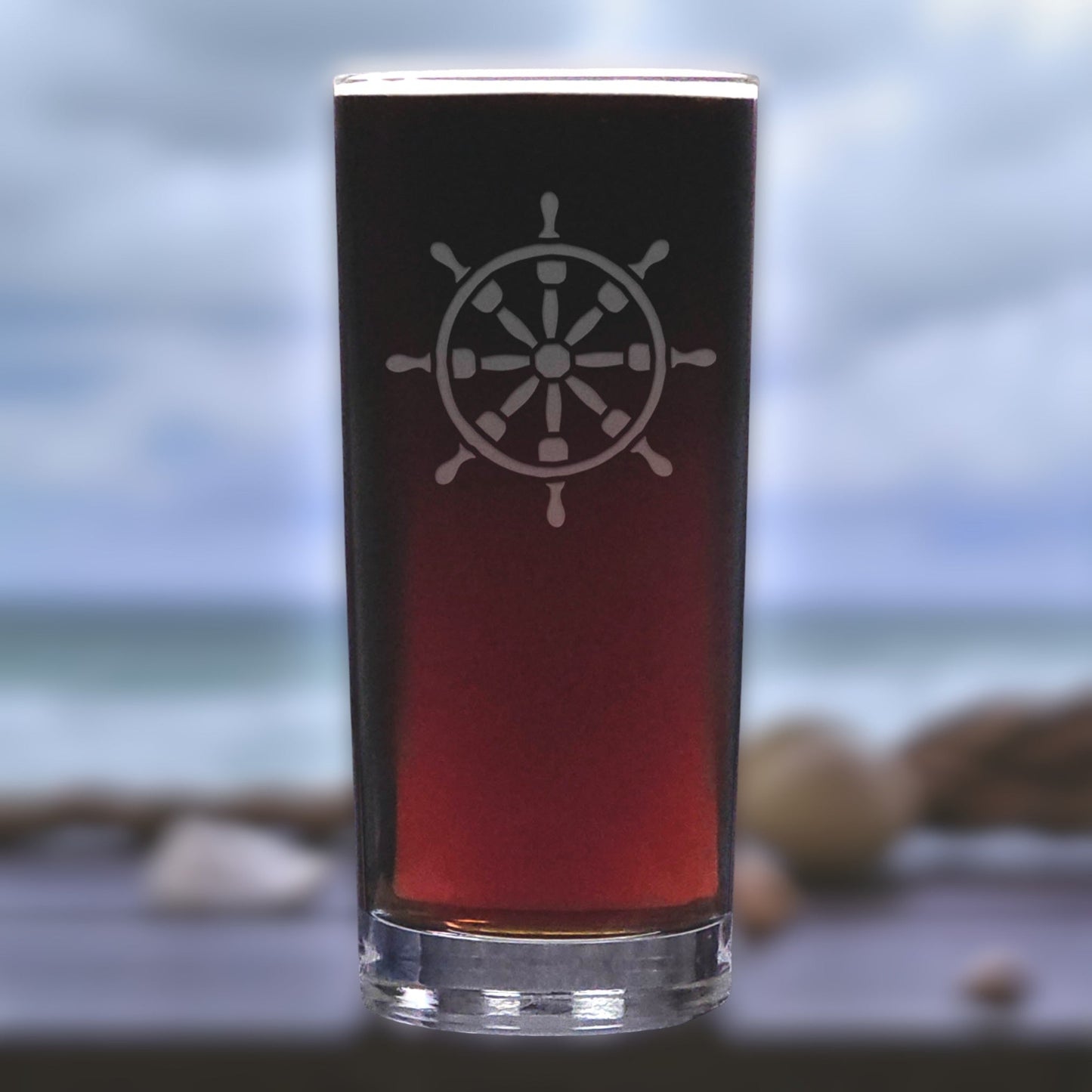Glass with a ship's wheel design on a blurred beach background
