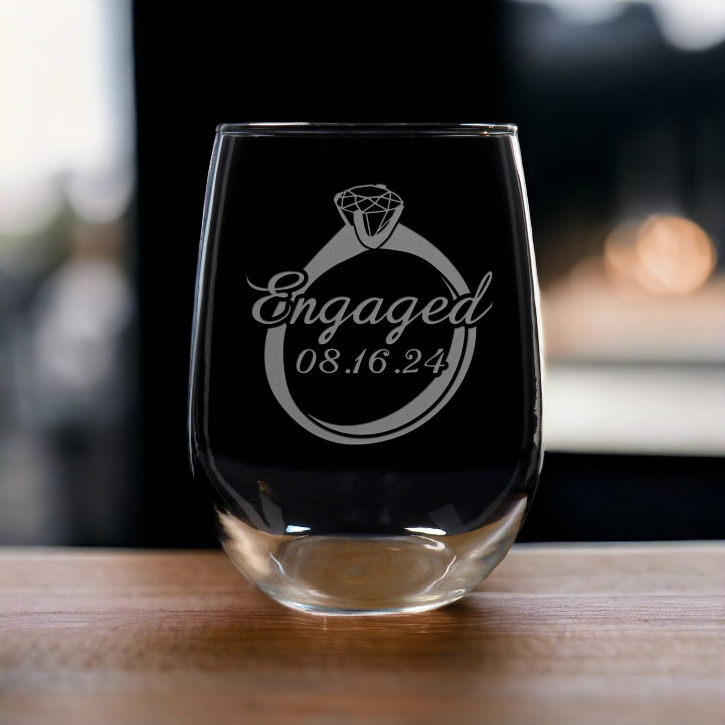 A set of 2 Stemless Wine Glass with the image of an engagement ring with the word "Engaged"and the date across the ring. - Copyright Hues in Glass