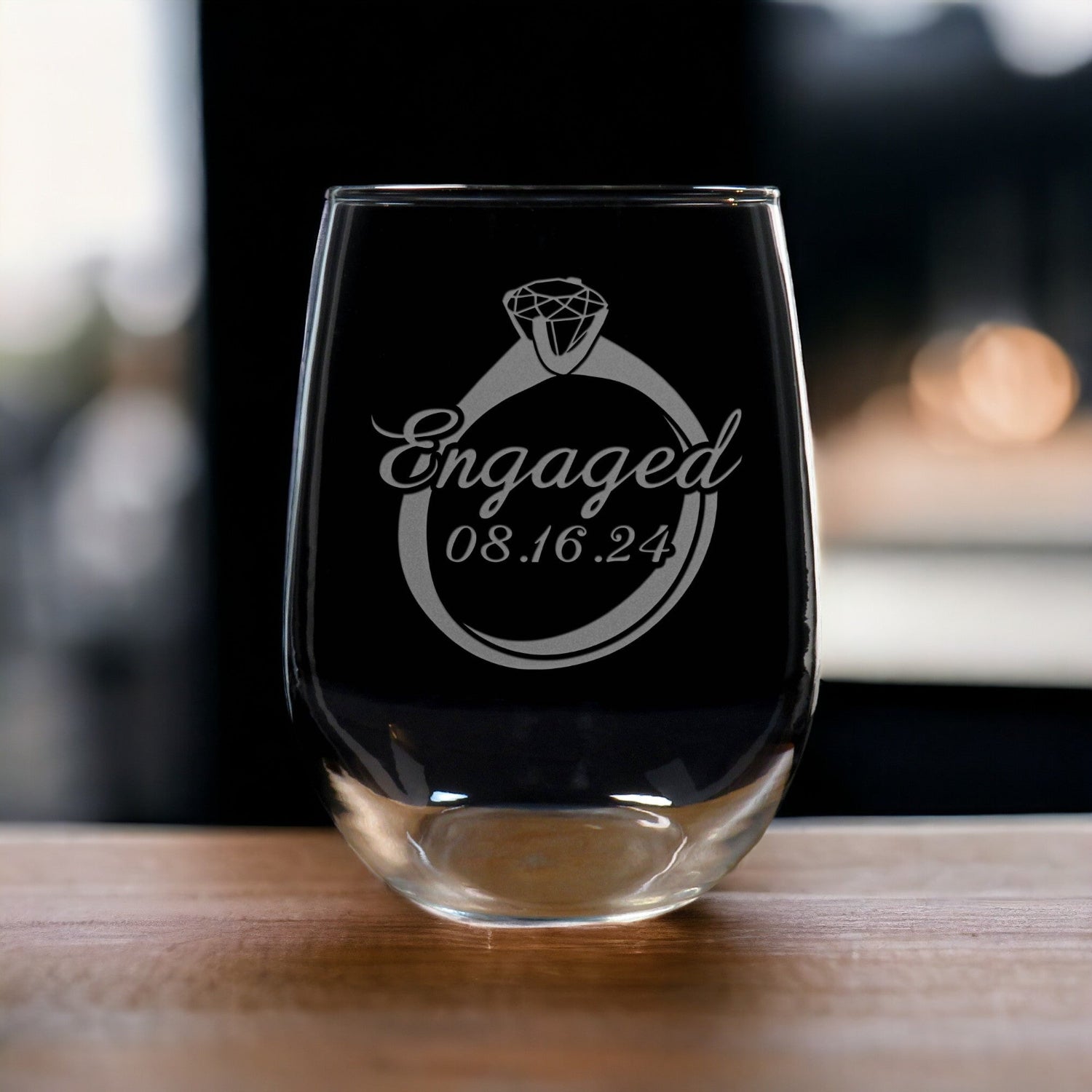 A set of 2 Stemless Wine Glass with the image of an engagement ring with the word "Engaged"and the date across the ring. - Copyright Hues in Glass