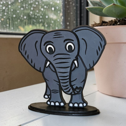 Gray elephant shelf sitter paintable MDF kit on a white surface with a potted plant in the background