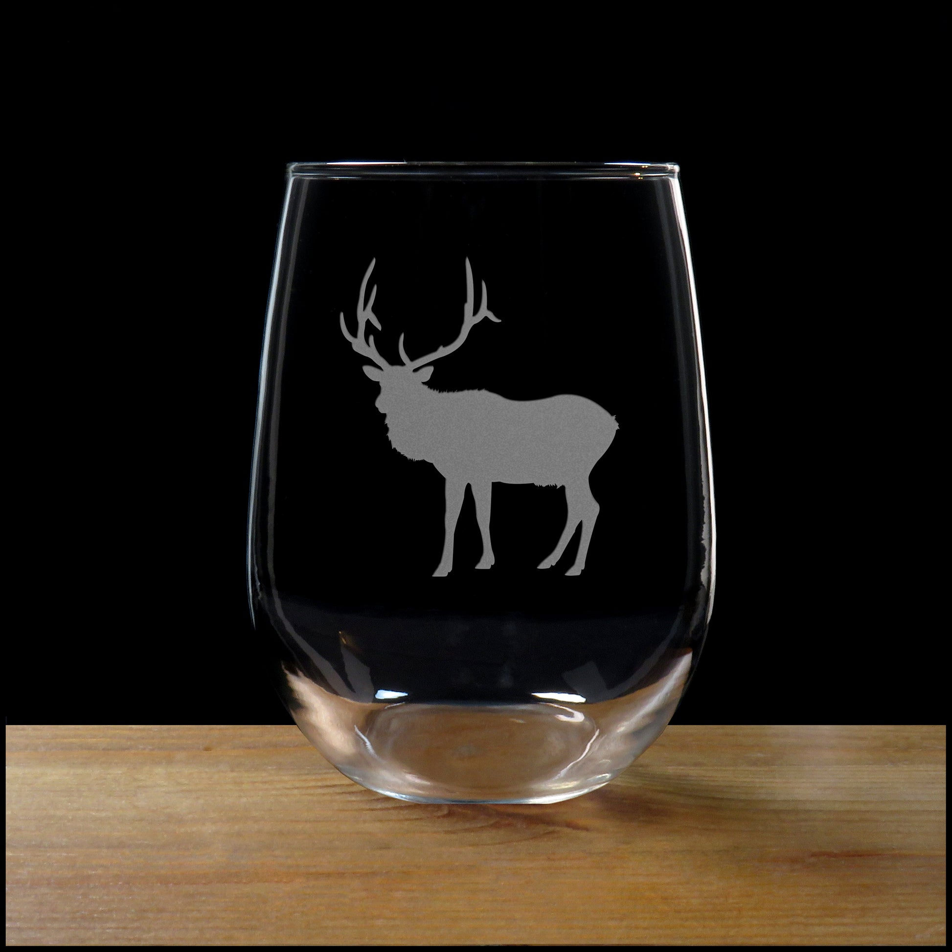 17oz Stemless Wine Glass with an etched image of an elk, on a wood surface and a black background