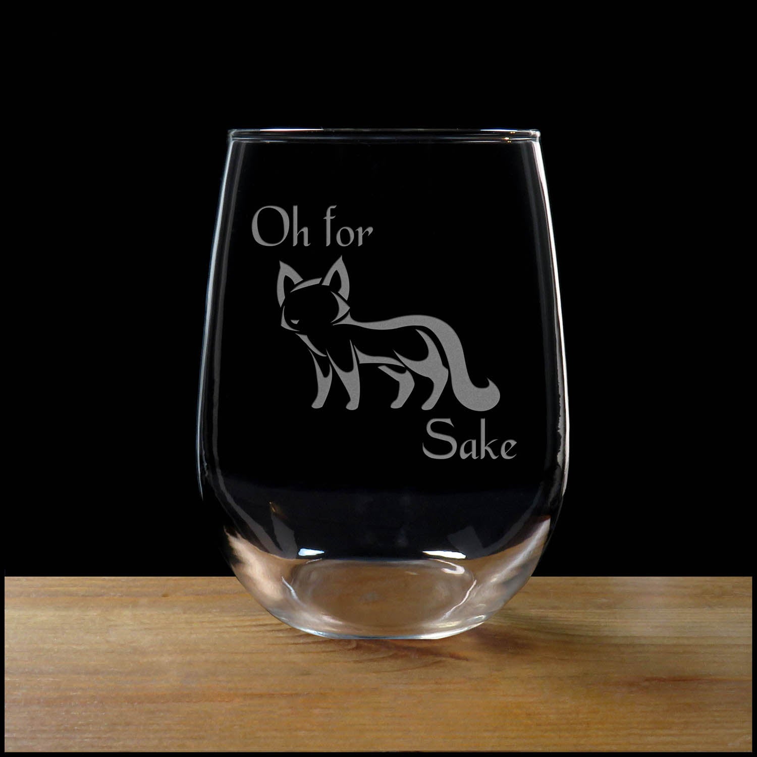 17oz Stemless Wine Glass with an etched image of a fox, on a wood surface and a black background