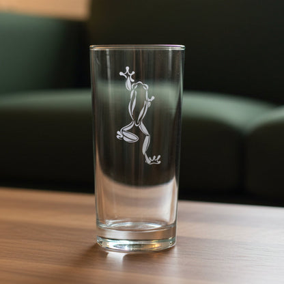 15oz Cooler Glass with an etched image of a climbing frog on a wood table and a green couch in the background