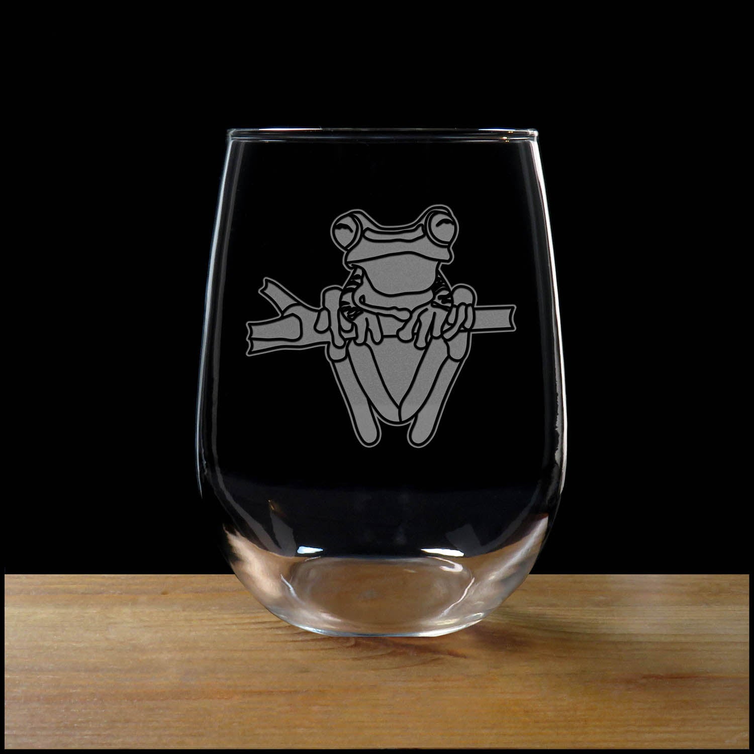 17oz Stemless Wine Glass with an etched image of a fox, on a wood surface and a black background