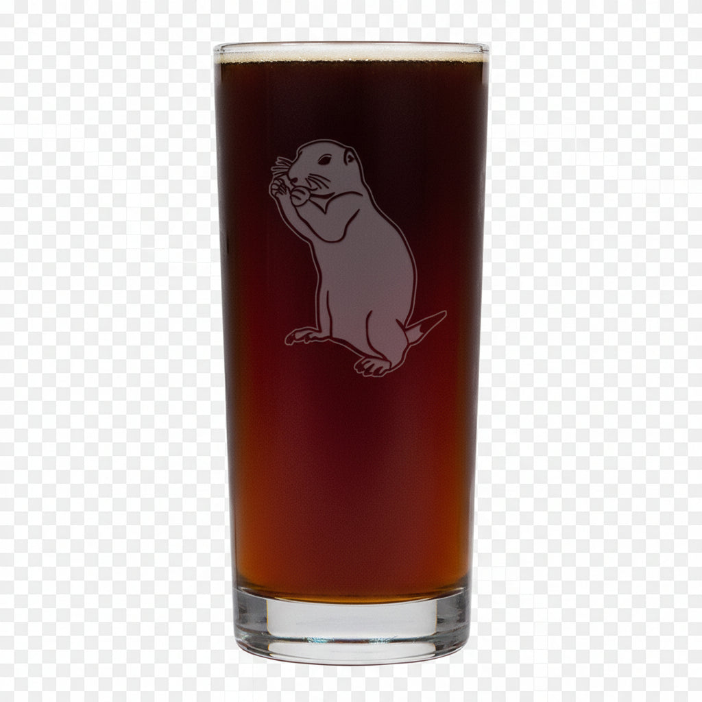 A tall, clear pint glass filled with dark amber beer, featuring an etched gopher  on a white background.