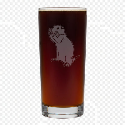 A tall, clear pint glass filled with dark amber beer, featuring an etched gopher  on a white background.