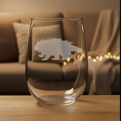 Clear glass with porcupine etching on it, sitting on a wooden surface and cozy livingroom in the background