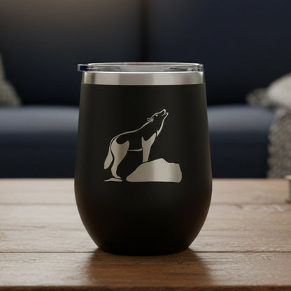 Black insulated tumbler with a wolf design on a wooden surface and white background