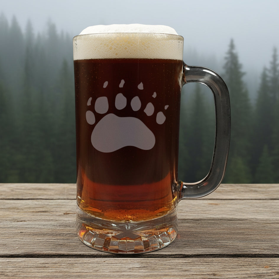 16oz Beer Mug with an etched image of a bear paw print with a background of a misty forest