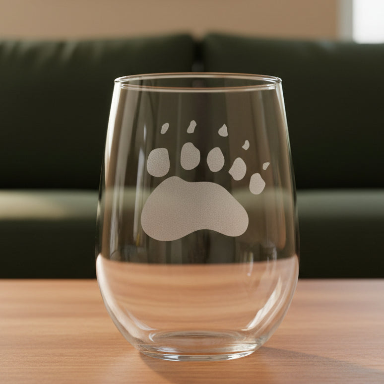 17oz Stemless Wine Glass with an etched image of a bear paw print and a green couch in the background