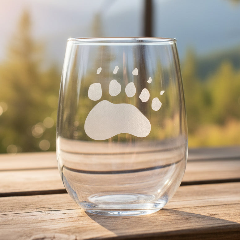 17oz Stemless Wine Glass with an etched image of a bear paw print with a background of a misty forest