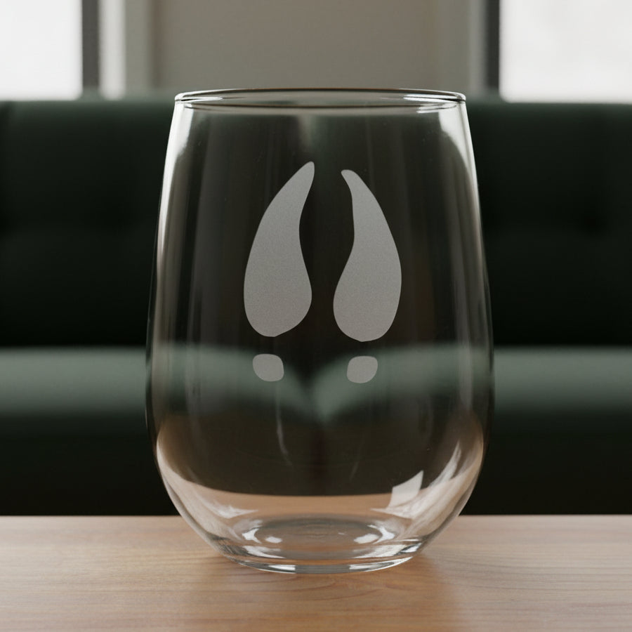17oz Stemless Wine Glass with an etched image of a deer track with a black couch in the background