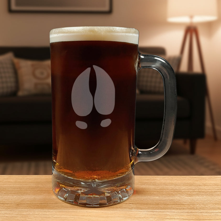 17oz beer mug with an etched image of a moose track and a black couch in a cozy room in the background