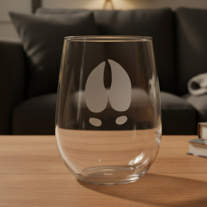 17oz Stemless Wine Glass with an etched image of a moose track and a black couch in the background