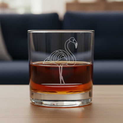 Glass with a flamingo design filled with red liquid with a blue couch in the background