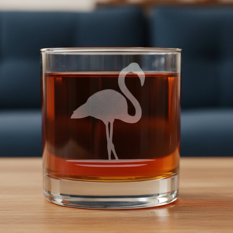 Glass with a flamingo design filled with red liquid with a blue couch in the background