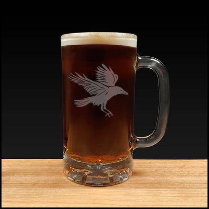 Glass mug with beer and a bird etching on a wooden surface and black background