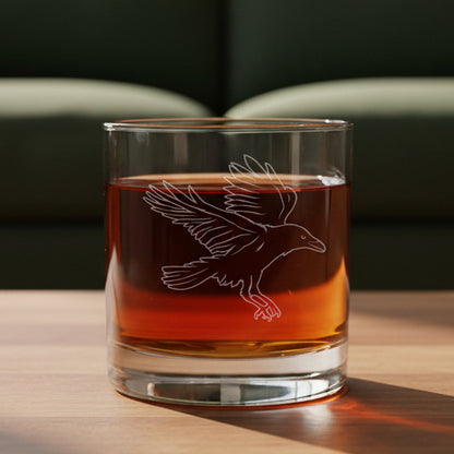 11oz whiskey glass with an Raven etching with a green couch in the background