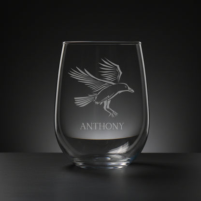 Clear glass with engraved bird design and 'ANTHONY' text on a wooden surface with grey background