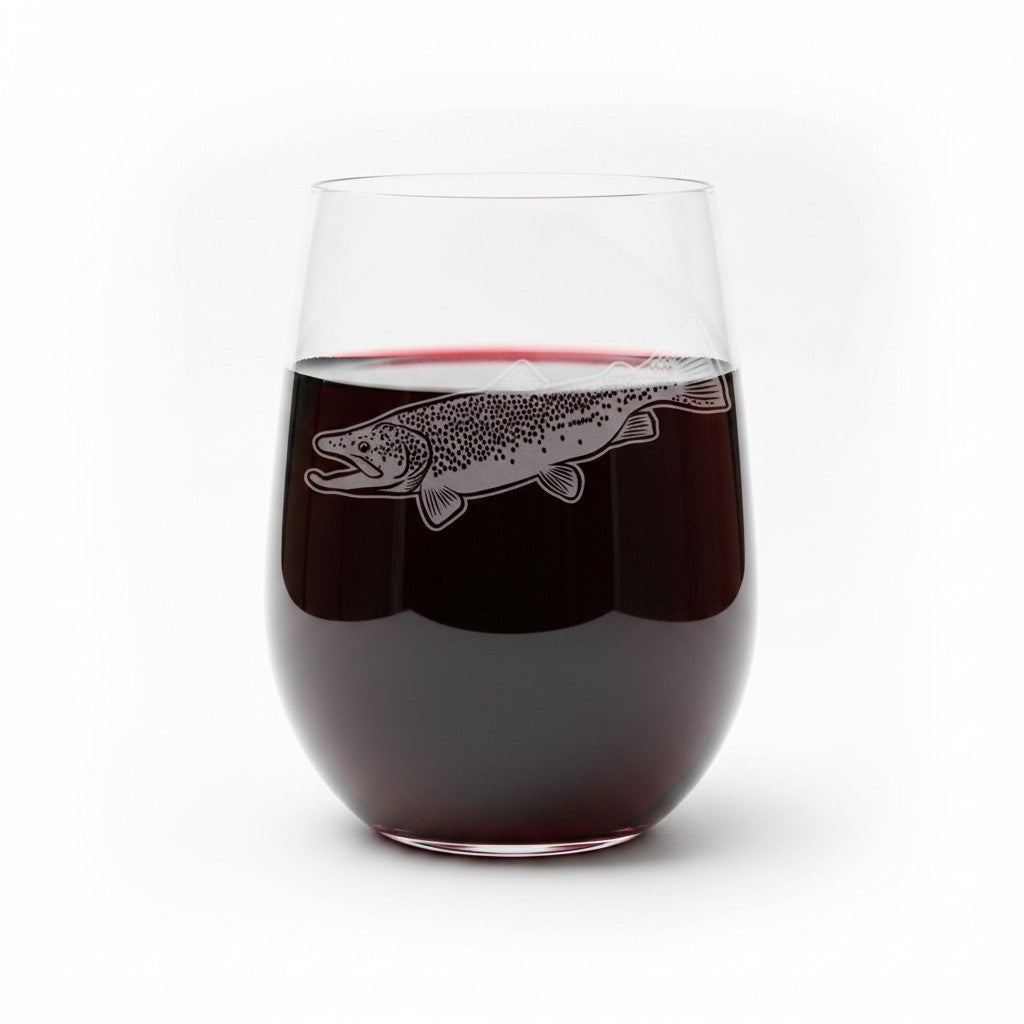 A clear stemless wine glass filled with red wine, featuring an etched fish design on the front, set against a plain white background.