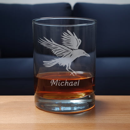 Glass tumbler with engraved bird design and 'Michael' text, filled with amber liquid on a wooden surface.