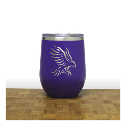 Purple tumbler with an eagle design on a wooden surface and white background