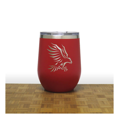 Red insulated tumbler with an eagle design on a wooden surface and white background