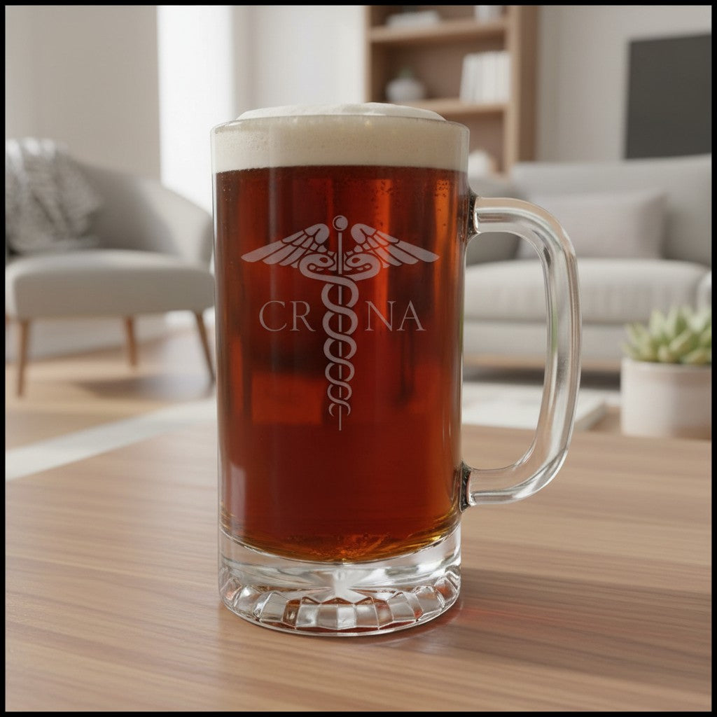A clear glass beer mug filled with amber beer and topped with white foam, standing on a wooden table in a softly blurred living room. The mug is etched with a medical caduceus symbol and the text 'CRNA'.