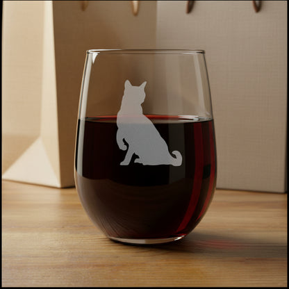 A clear stemless wine glass with a gray etched silhouette of a sitting cat, displayed on a wooden surface 