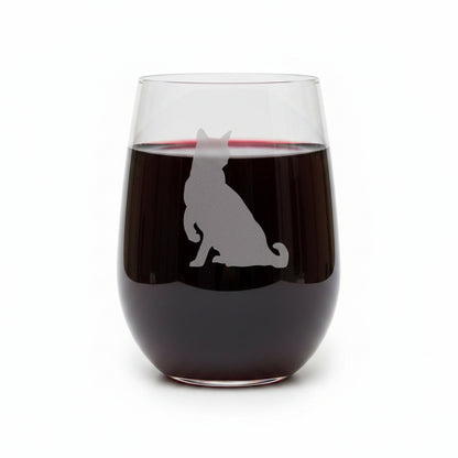A clear stemless wine glass with a gray etched silhouette of a sitting cat, displayed on a wooden surface against a solid white background.