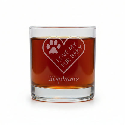 A clear glass rocks tumbler filled with amber liquid, featuring an etched heart design with a paw print and the words 'LOVE MY FUR BABY' along with the name 'Stephanie' below, set against a white background.