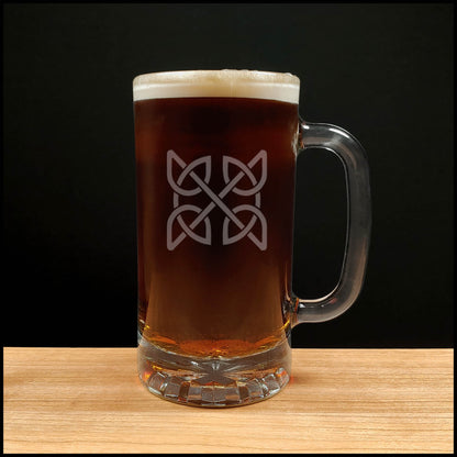 Glass mug with a Celtic knot design filled with dark beer on a wooden surface.