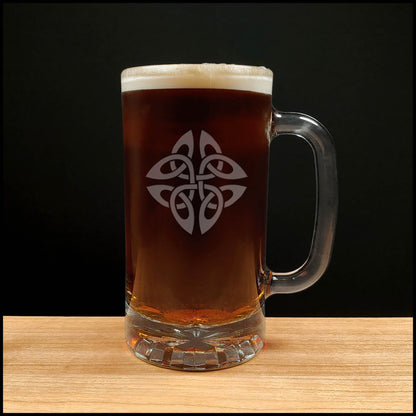 Glass mug with Celtic knot design filled with beer on a wooden surface and black background