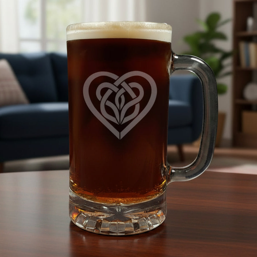 Glass mug with a heart-shaped Celtic knot design filled with dark beer on a wooden surface.