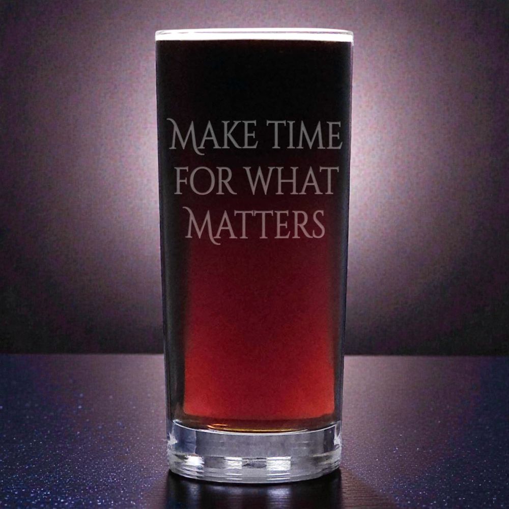 Glass with red liquid and motivational text, “Make Time for Those Who Matter” on a dark background
