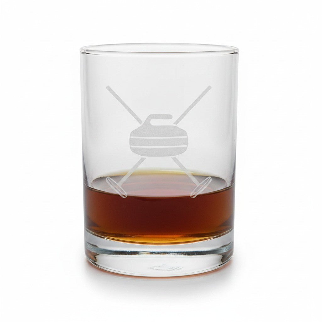 A clear glass rocks tumbler with an etched curlingdesign, partially filled with an amber-brown liquor, on a white background.