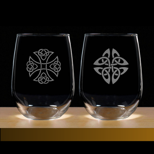 Two clear glasses with Celtic knot designs on a wooden surface and black background