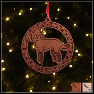 A round cherry wood veneer ornament with a border of small paw prints. The center of the ornament is a labradoodle dog