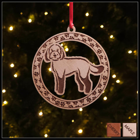 A round maple wood veneer ornament with a border of small paw prints. The center of the ornament is a labradoodle dog