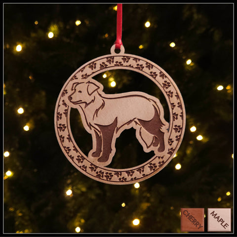 A round maple wood veneer ornament with a border of small paw prints. The center of the ornament is a border collie dog