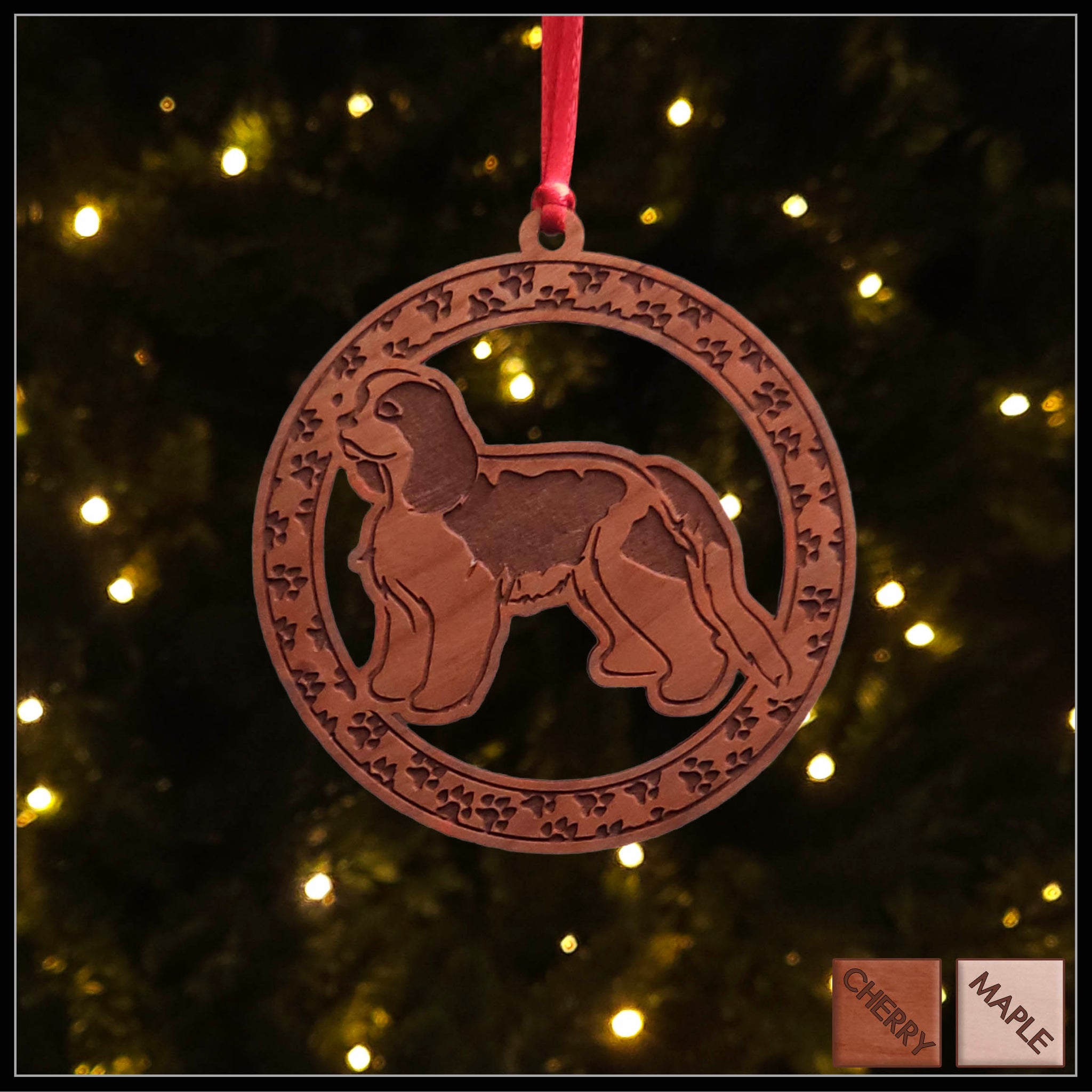 A round cherry wood veneer ornament with a border of small paw prints. The center of the ornament is a Cavalier King Charles dog.