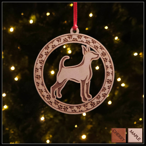 A round maple wood veneer ornament with a border of small paw prints. The center of the ornament is a Doberman dog.
