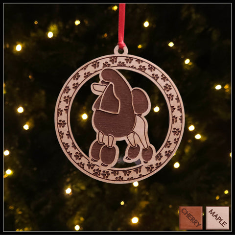  A round Maple wood veneer ornament with a border of small paw prints. The center of the ornament is a Poodle dog.