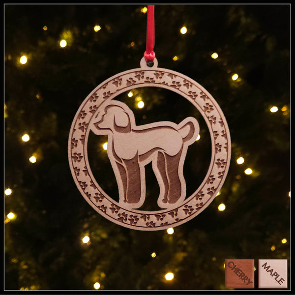 A round Maple wood veneer ornament with a border of small paw prints. The center of the ornament is a A round Maple wood veneer ornament with a border of small paw prints. The center of the ornament is a Poodle dog.