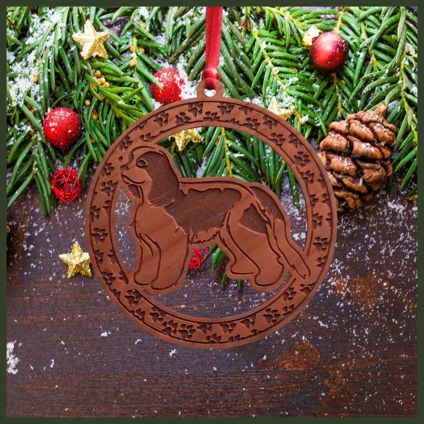 A round cherry wood veneer ornament with a border of small paw prints. The center of the ornament is a Cavalier King Charles dog.