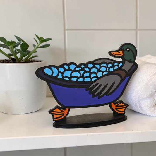 Decorative duck shelf sitter finished kit with bathtub on a shelf next to a plant and towel